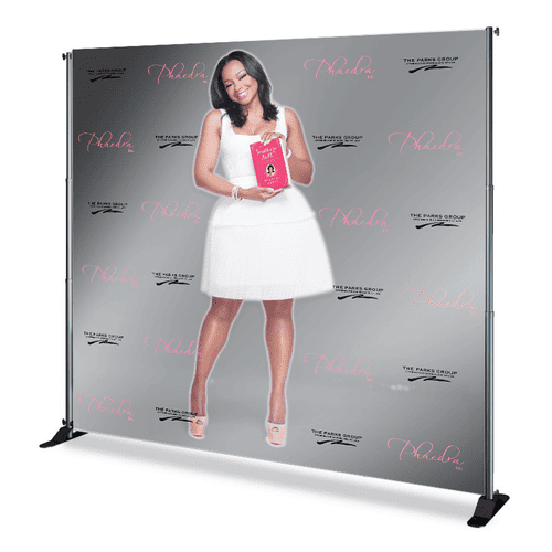 Woman in a white dress holding a pink book on a branded backdrop